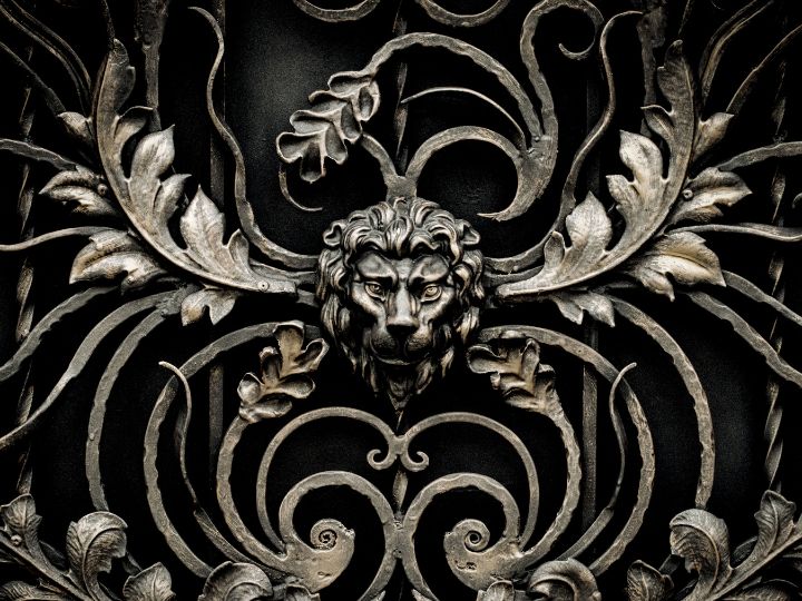 Intricately crafted metal gate featuring a lion's head surrounded by ornate scrollwork and floral patterns, symbolizing the path through divorce mediation offered by Fairway Divorce Solutions.